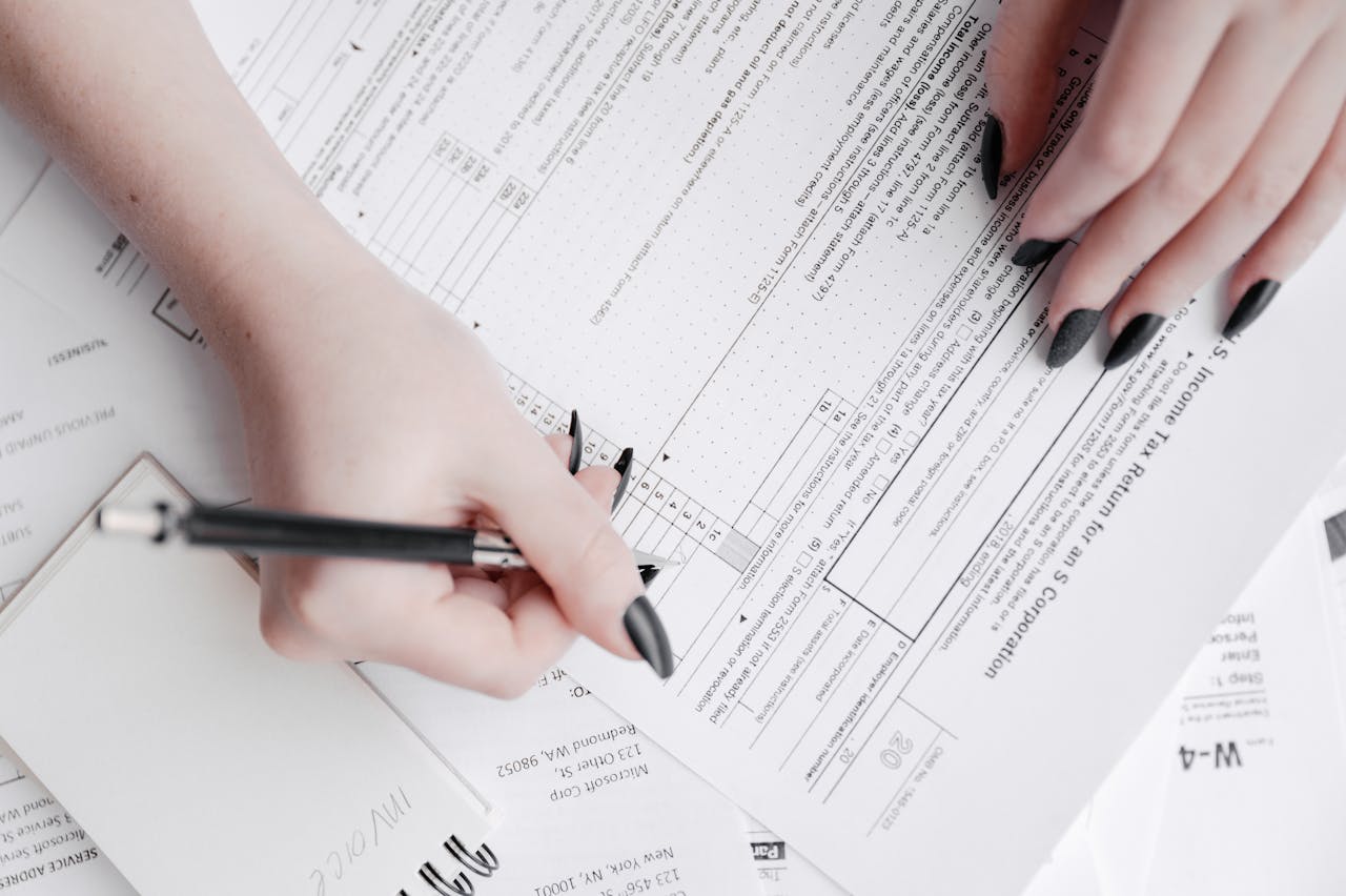 services-04 A detailed close-up of a woman filling out tax forms with a pen. Ideal for finance themes.
