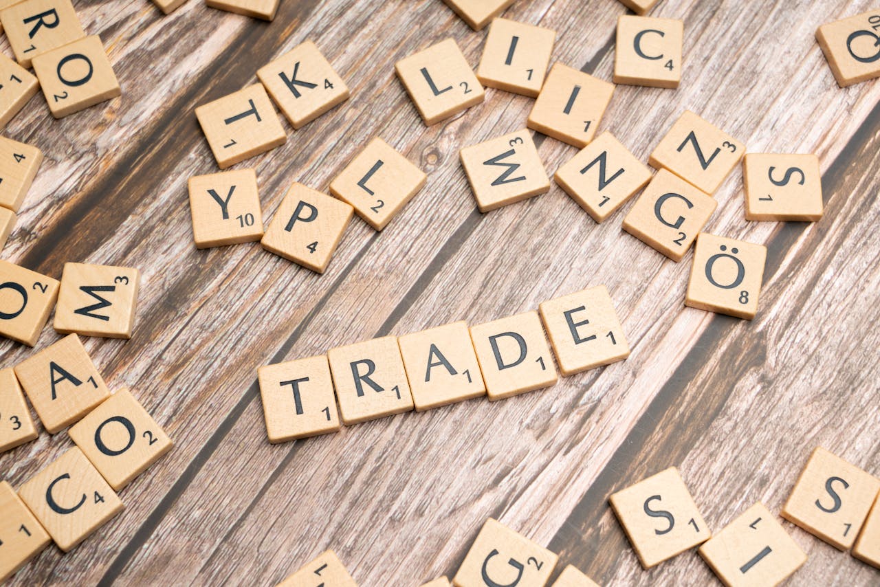 process-img Scrabble letter tiles spelling trade on a wooden surface, illustrating business concepts.